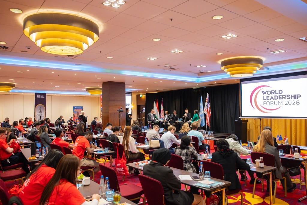 Plenary session with global stage screens and delegates seated in the audience